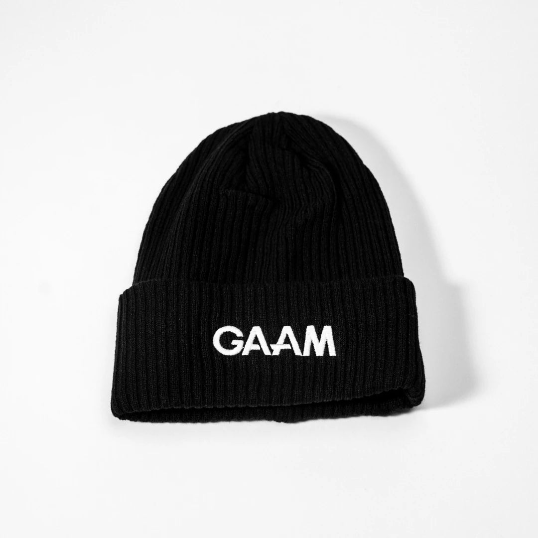 GAAM Beanie Black, musta joustinneulottu pipo käännetyllä reunalla ja selkeällä valkoisella logolla edessä.