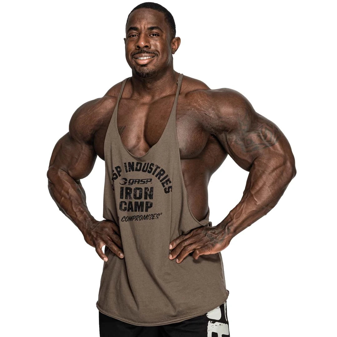 Vihreä puuvillainen GASP Stringer Tank Washed Green -treenitoppi miesmallilla, syvät kädentiet ja suuri etupainatus.
