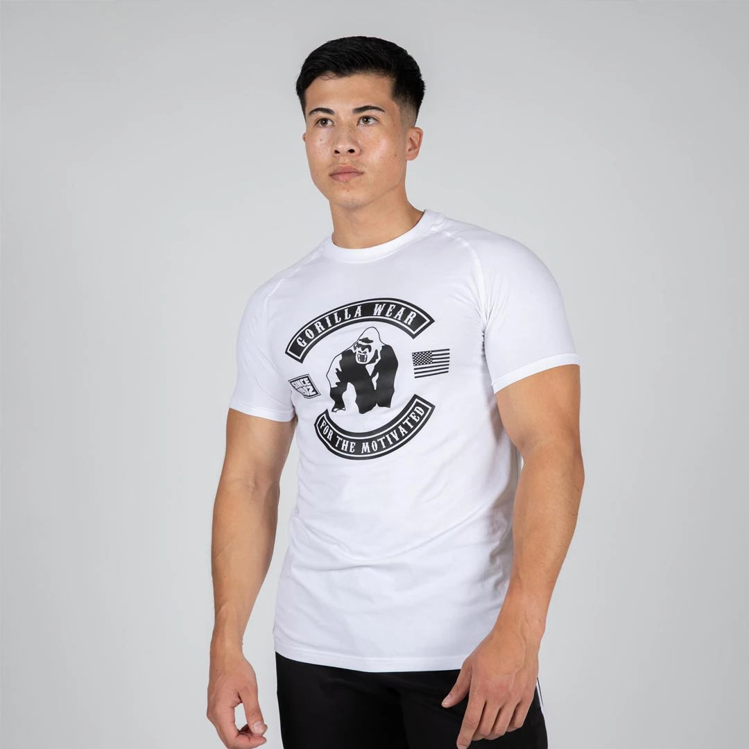 Mies yllään Gorilla Wear Tulsa T-Shirt White, valkoinen vartalonmyötäinen treenipaita isolla mustalla logolla., kuva 2/3