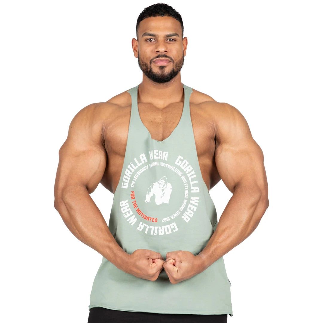 Vaaleanvihreä Gorilla Wear Melrose Stringer Green -treenitoppi valkoisella logolla ja syvillä kädenteillä miehen yllä., kuva 3/7