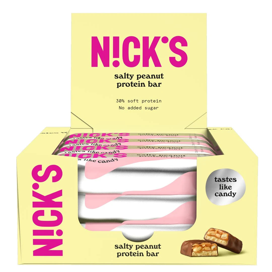 12 x NICKS Soft bar 50 g Salty Peanut keltaisessa laatikossa, jossa on hopea-pinkkejä patukoita ja jaettu pala.