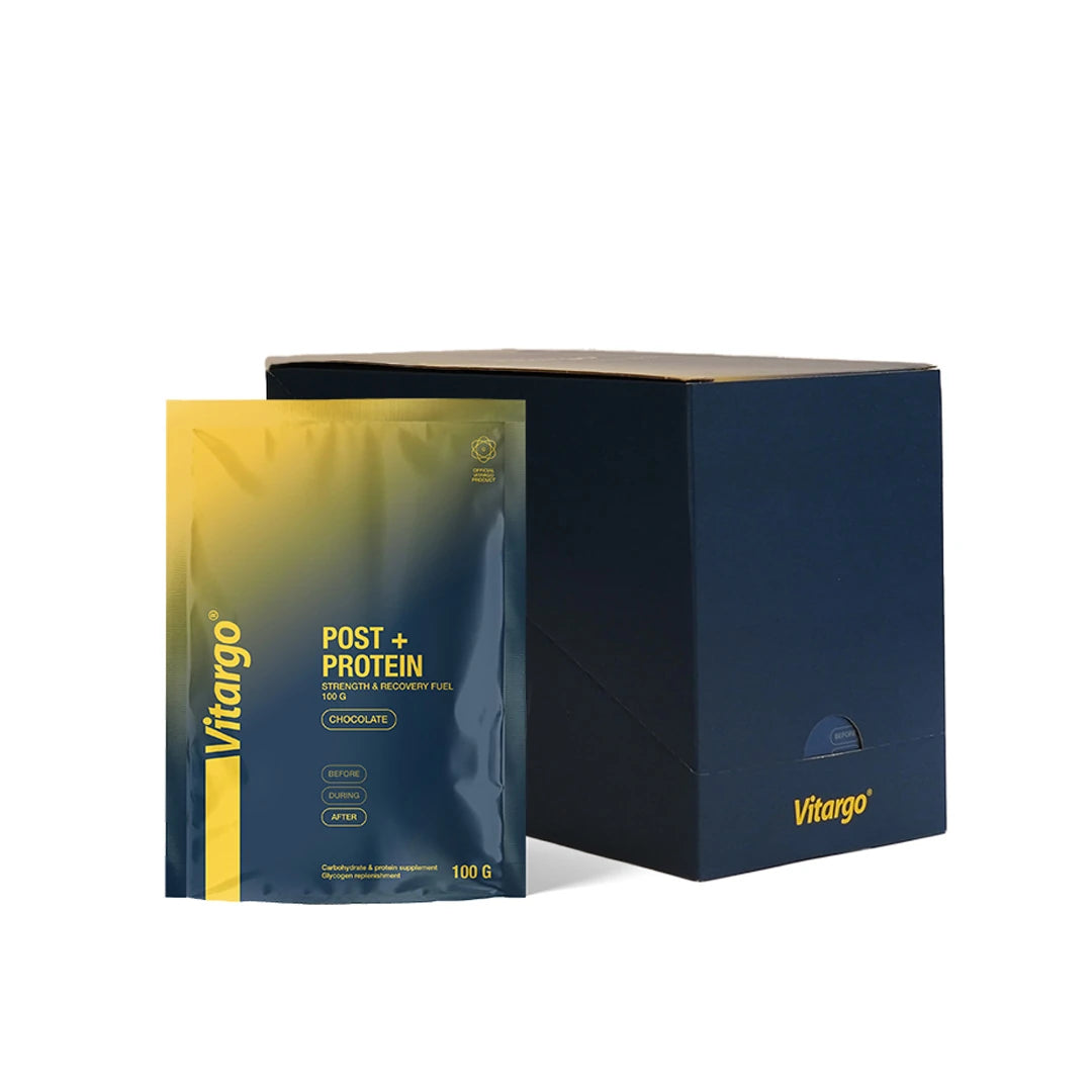 Vitargo Post Protein 15 x 100 g suklaa, tummansininen ja keltainen annospussi tummansinisen pahvilaatikon vieressä.