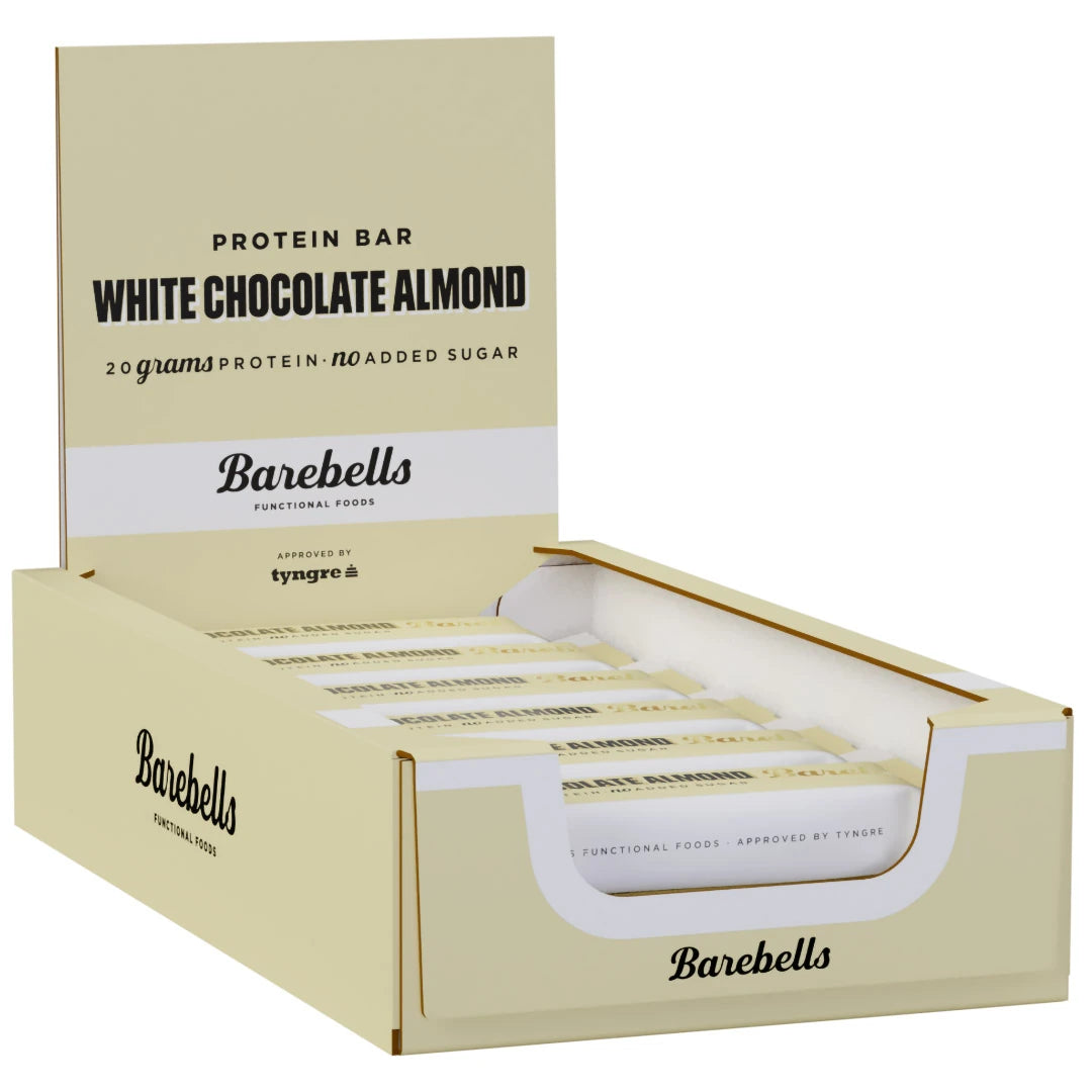 12 x Barebells Protein Bar 55 g White Chocolate Almond beigessä laatikossa valkoisilla ja mustilla yksityiskohdilla.