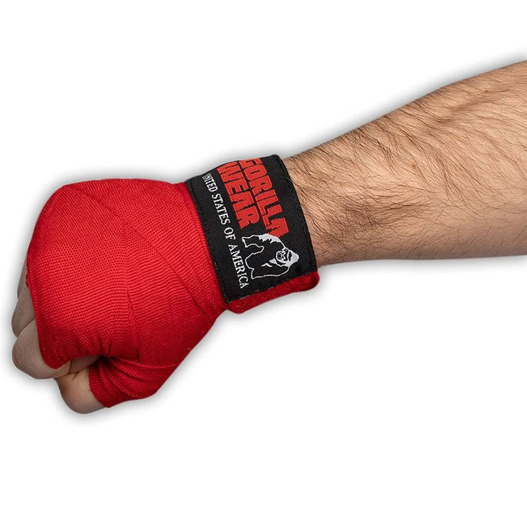 Gorilla Wear Boxing Hand Wraps Red kiedottuna puristetun nyrkin ympärille, punaista puuvillaa mustalla tarranauhalla.