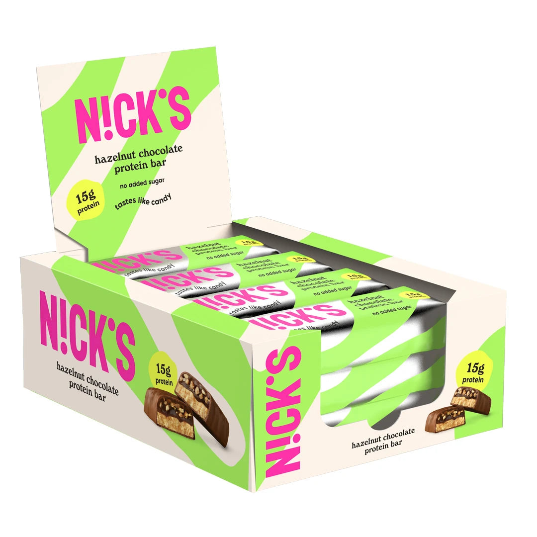 12 x NICKS Soft bar 50 g Hazelnut Chocolate valkoisessa esittelylaatikossa vihreillä yksityiskohdilla ja pinkillä logolla.