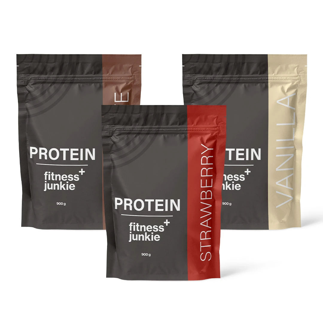 3 x fitnessjunkie Protein 900 g -heraproteiini kolmessa mustassa pussissa ruskein, punaisin ja beigein yksityiskohdin.