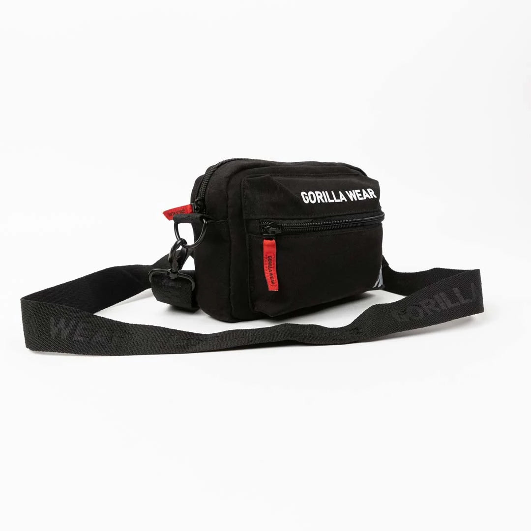 Gorilla Wear Brighton Crossbody Bag Black -olkalaukku hihnalla, valkoisilla logoilla ja punaisilla yksityiskohdilla.